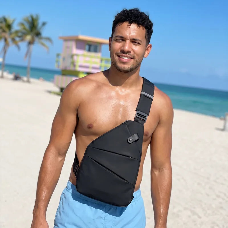 Hombre sin camisa en la playa de Miami con bolso antirrobo negro cruzado sobre el pecho