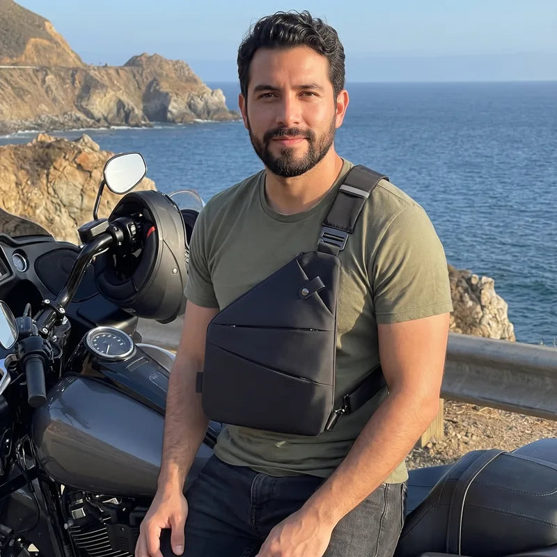 Motociclista sentado en su moto frente al mar con bolso antirrobo negro bien ajustado al pecho
